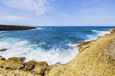 Aruba 'daki Arikok Ulusal Parkı' nın Rocky sahili. Turkuaz Karayip Denizi dalgaları engebeli uçurumlara çarpıyor..
