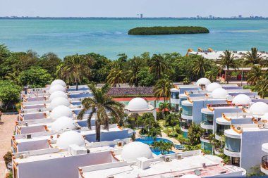 Turkuaz lagün Karayip denizi ve palmiye ağaçları yakınında kubbeli çatıları olan tropikal villaların hava manzarası. Meksika mı? Cancun..