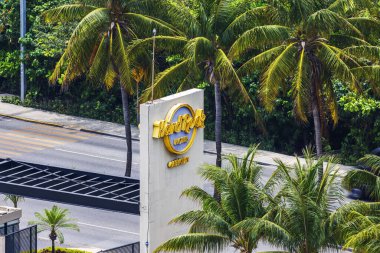Hard Rock Hotel Cancun giriş tabelası yeşil tropikal palmiye ağaçları ve parlak güneş ışığında canlı yapraklarla çevrili. Meksika mı? Cancun.. 
