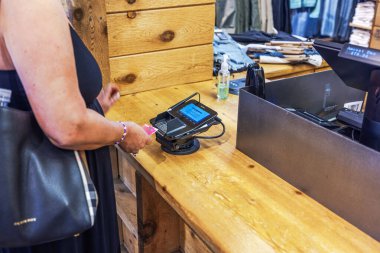 Müşteri kredi kartını Levi 'ın giyim mağazasının kasası sırasında ahşap tezgahın üzerindeki ödeme terminaline sokuyor. - New York. ABD. 