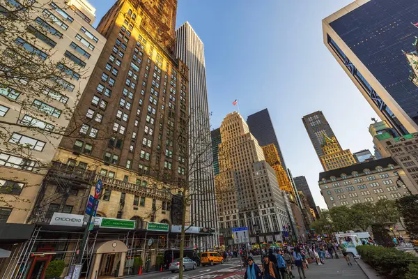 Yayalar, sarı taksiler, modern ve tarihi gökdelenler altın günbatımı ışığıyla aydınlatılan Manhattan caddesi. - New York. ABD. 
