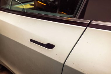 Arabanın kapı kolunun yakın görüntüsü beyaz araçta görünür toprak izleri ve pencerenin iç kısımlarının yansıması var. İsveç.