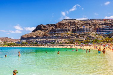 İnsanlar Atlantik Okyanusu manzaralı sahillerinde kristal berraklığında turkuaz suyun tadını çıkarıyorlar. Etrafı kayalık uçurumlar ve otellerle çevrili. Gran Kanaryası, Las Palmas, İspanya. 