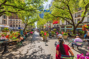 İnsanlar güneşli bir bahar gününde New York 'taki Herald Square Park' ta yeşillik ve çiçeklerle dinleniyorlar. - New York. ABD.