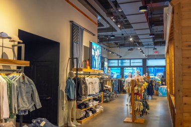 Levi 'nin mağazasının içinde katlanmış tişörtler, kot pantolonlar ve parlak ışık altında aksesuarlar sergileniyor. - New York. ABD.