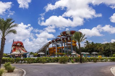 Yılan temalı cazibe, tropik palmiye ağaçları ve bulutlu mavi gökyüzü de dahil olmak üzere geniş renkli slaytlarla dolu bir su parkı.. 