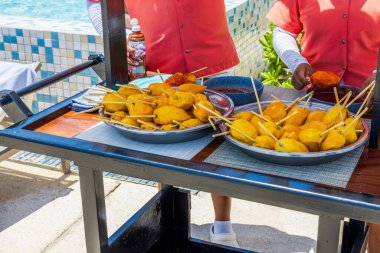 Havuz kenarındaki tropikal tatil beldesinde metal tepsilerde servis edilen şişler üzerinde taze soyulmuş mangolar. Meksika mı? Cancun..