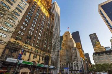 Uzun gökdelenler ve Manhattan 'daki tarihi binalar. New York' ta ilkbaharda cam cephelerde güneş ışığı yansıyor. ABD.