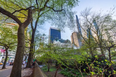 Baharda Manhattan Central Park 'ta yeşil ağaçlar modern gökdelenler ve arka planda tarihi binalar. - New York. ABD.