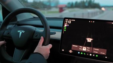 Tesla Model 3 'ü kullanan kadın otoyolda yüksek hızda gidiyor. Dijital paneli otomatik pilot navigasyonunu gösteriyor.. 