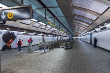 New York 'ta 96. Cadde' deki modern metro istasyonu yürüyen merdivenleri, yolcuları ve beyaz fayanslı duvarları var. - New York. ABD.