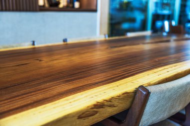 Otel lobisinde doğal kenarları ve sandalyeleri olan cilalanmış ahşap masa, sıcak tonlarda ve modern iç tasarım içeriyor. Meksika.