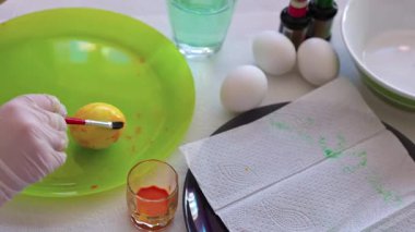 Paskalya yumurtasını fırçayla tabakta yuvarlayan çocuk boya kalıpları yaratıyor. İsveç.