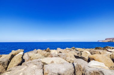 Atlantik Okyanusu 'nun kayalık kıyı şeridi Gran Kanaryası üzerinde açık mavi gökyüzü altında.