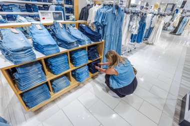 Kadın, Macys mağazasının moda bölümünde kot pantolon seçiyor. - New York. ABD.