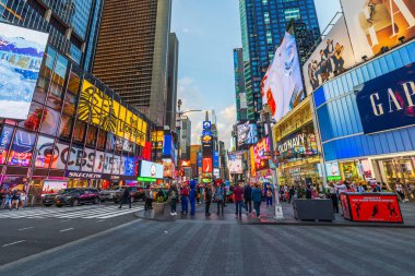 Kalabalık Times Meydanı 'nda parlak reklam panoları ve alacakaranlıkta şehrin ışıklarıyla yürüyor. New York.