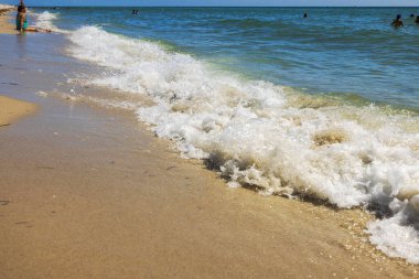 İnsanlar Atlantik Okyanusunda yüzerken dalgalar güneşli bir günde Miami Sahili 'nin kumlu sahillerini yıkıyor. Miami Plajı. ABD.