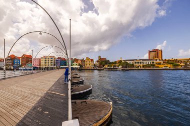 Willemstad 'daki St. Anna Körfezi üzerindeki Kraliçe Emma Köprüsü' nde bulutlu mavi gökyüzünün altında renkli koloni binaları var. Willemstad. Curacao.