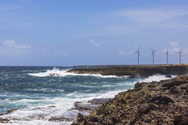Arikok Ulusal Parkı, Aruba 'daki rüzgar türbinlerinin yakınındaki kayalık sahil şeridine çarpan dalgalar.