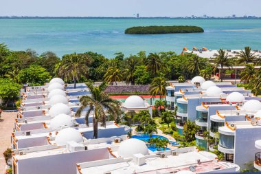 Güneşli bir günde Karayip Denizi yakınlarında palmiye ağaçları ve havuzu olan beyaz kubbeli villalar..