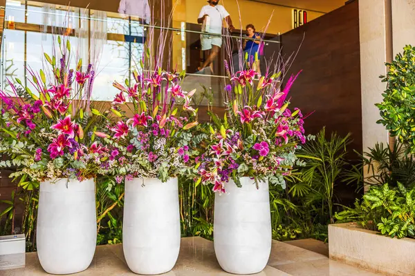 Beyaz vazolardaki parlak pembe çiçek aranjmanları modern otelin içini tropikal bitkilerle süslüyor. Meksika mı? Cancun.. 