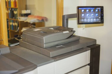 Kontrol paneli ve bulanık arkaplan kitaplığı olan ofis fotokopi makinesinin görüntüsünü kapat. İsveç.