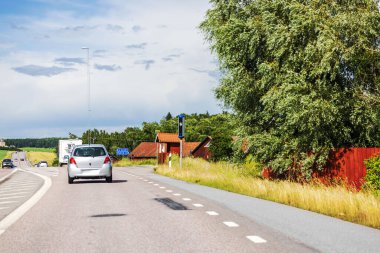 Kırsal yolda hız kontrol kameraları yerleştirildi. Arabalar küçük köye doğru gidiyor. İsveç.