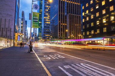 Akşamları şehrin beşinci caddesinde aydınlık binalarla birlikte hareket eden arabaların yol izleri. - New York. ABD. 