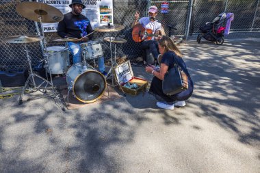 Sokak müzisyenleri bateri ve gitar çalarken kadınlar açık hava gösterisi sırasında para bağışlıyor. - New York. ABD. 