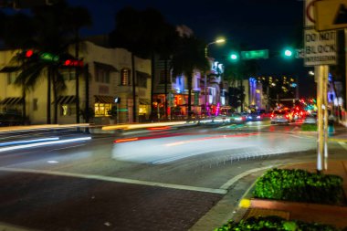 Miami 'de Collins Bulvarı' ndaki gece sahnesinde araba farları ve parlayan sokak lambaları vardı..