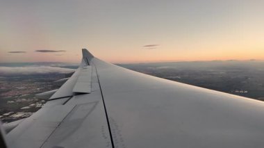 Gün doğumunda Madrid banliyölerindeki uçak penceresinden uzak ufukta alçak bulutlar ve kanatlar görünüyor. İspanya.