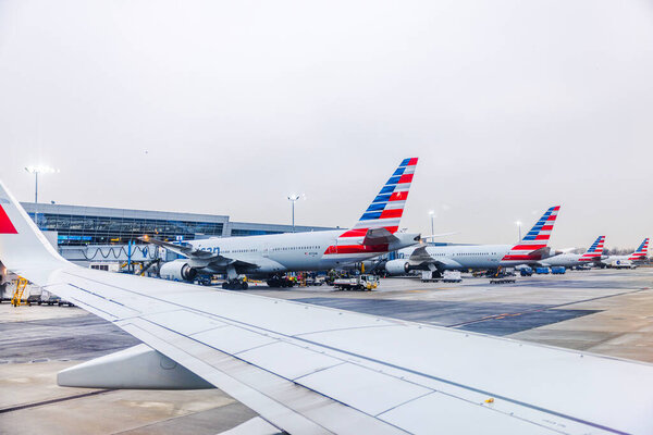 Самолеты American Airlines припарковались у терминальных ворот аэропорта Кеннеди в дождливое утро, вид через окно самолета после посадки. Нью-Йорк. США. 