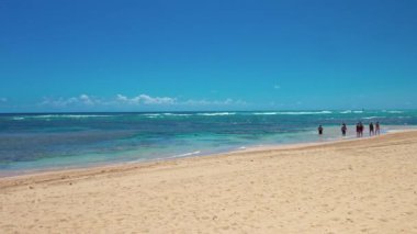 Dominik kumlu sahillerinde turkuaz Atlantik Okyanusu 'yla sığ sularda yürüyen turistler. Punta Cana. Dominik Cumhuriyeti. 