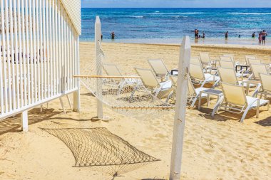 Boş hamak ve kumlu sahilde beyaz şezlonglar Atlantik Okyanusu 'na bakan turistlerle dolu. Dominik Cumhuriyeti. Punta Cana.
