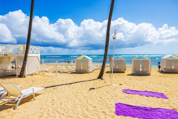 Güneşli yatakları ve kumlu sahilde Atlantik Okyanusu 'na bakan beyaz gölgelikleri olan özel dinlenme odaları. Dominik Cumhuriyeti. Punta Cana. 