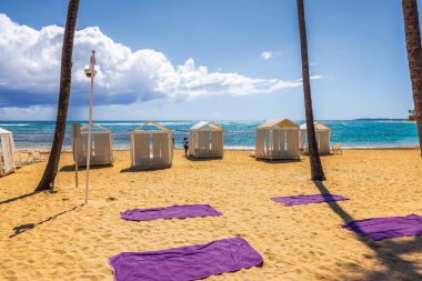 Plaj kenarındaki kabinlerde şezlonglar ve Atlantik Okyanusu 'na bakan masalar güneşli gökyüzünün altında bulutlarla. Punta Cana. Dominik Cumhuriyeti.