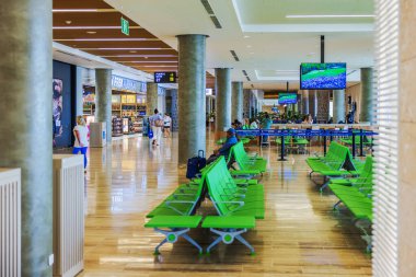 Yeşil sandalyeleri, gümrüksüz mağazası ve yanından geçen yolcuları olan geniş bir havaalanı bekleme alanı. Punta Cana. Dominik Cumhuriyeti. 