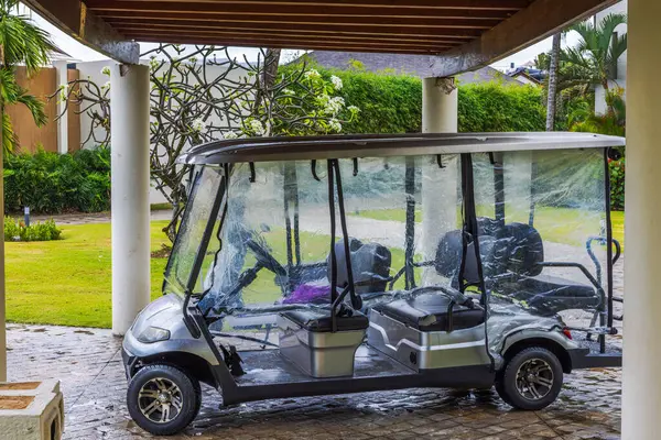 Yağmurlu havalarda tropik otellerin çatısının altında park etmiş elektrikli golf arabası. Punta Cana. Dominik Cumhuriyeti.