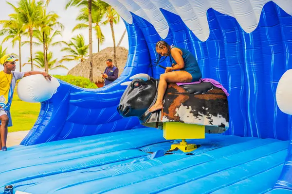 Plajdaki kadın tropikal cazibede şişme mekanik boğaya binerken konsantre oluyor. Punta Cana. Dominik Cumhuriyeti. 