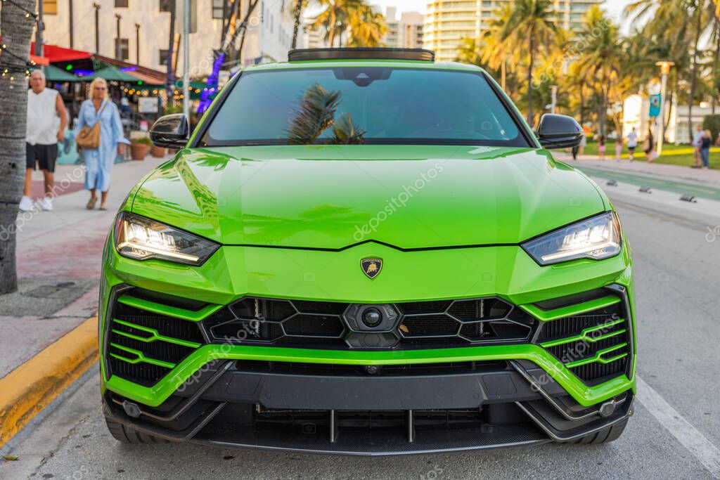 Front view of green Lamborghini Urus with headlights on, parked on Ocean Drive in Miami Beach. Miami Beach. USA.