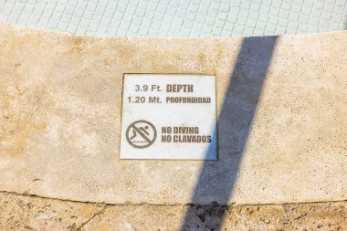 Havuz kenarındaki derinlik uyarısı, dalış sembolü ve iki dilli metni olmayan 3.9 ft ve 1.20 m 'yi gösteriyor. Punta Cana. Dominik Cumhuriyeti.