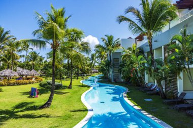 Punta Cana tatil köyünün açık hava manzarası palmiye ağaçları, yeşil çimenler ve otel odaları boyunca özel havuz. Dominik Cumhuriyeti. Punta Cana. 