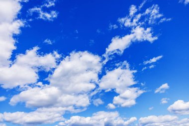 Beyaz bulutlar parlak gün ışığında mavi yaz gökyüzünde süzülüyor. İsveç.