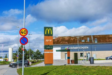 McDonalds ve Grnbystaden AVM işaretleri park alanının yakınında arabalar ve yol işaretleri var.. 