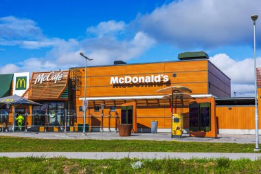 McDonalds binası McCafe ve açık hava büfesi İsveç banliyösünde bulutlu mavi gökyüzü altında.. 