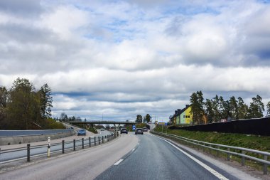 Sarı mağaza binası ve köprünün yanındaki karayolu kavşağının manzarası bulutlu bir gökyüzünün altında..