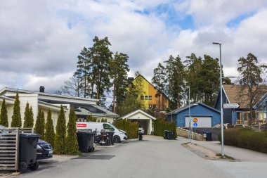 Renkli cepheli Avrupa villaları ve beyaz bulutlu mavi gökyüzünün altında sessiz cadde boyunca çam ağaçları..