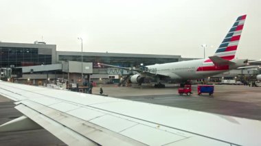 JFK havaalanındaki yolcu uçağından yolcu köprüsüne bağlı Amerikan Hava Yolları uçağının görüntüsü. - New York. ABD.