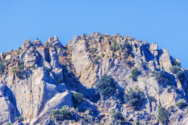 Rocky Dağı zirvesi engebeli uçurumlar ve Kos adasındaki açık mavi gökyüzünün altında yeşil çalılar. Yunanistan.