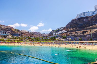 Turistler, Gran Kanarya adasındaki turkuaz suyu ve kayalık tepelerle Amadores Sahili 'nde dinleniyor ve yüzüyorlar. Büyük Kanarya. İspanya. 